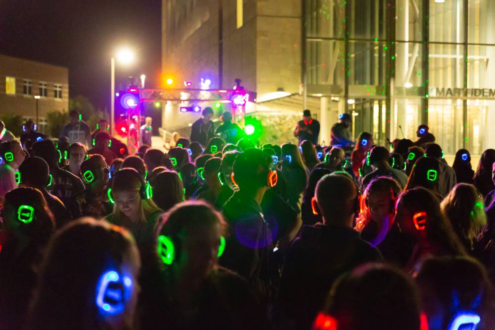 student crowd with colored LED headphones participating in GVSU's silent disco